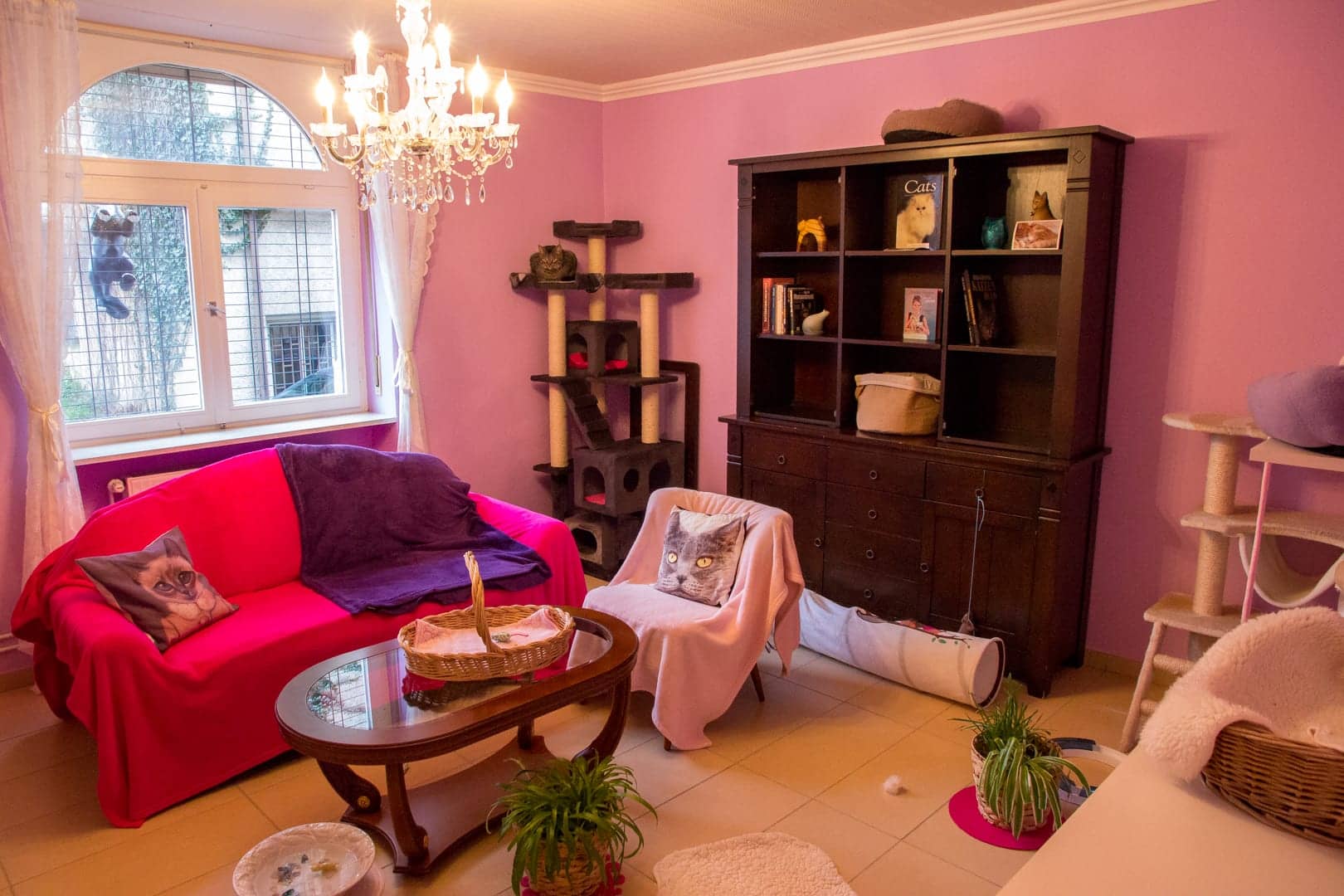 Altrosa Zimmer mit Kronleuchter, pinkem Sofa und dunklem Buffetschrank